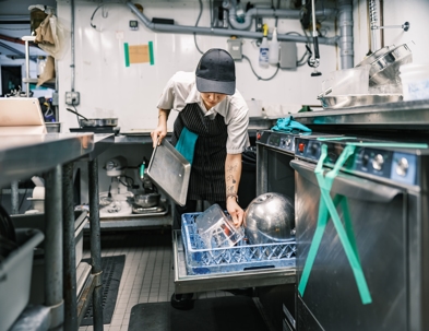 woman cleaning kitchen equipment